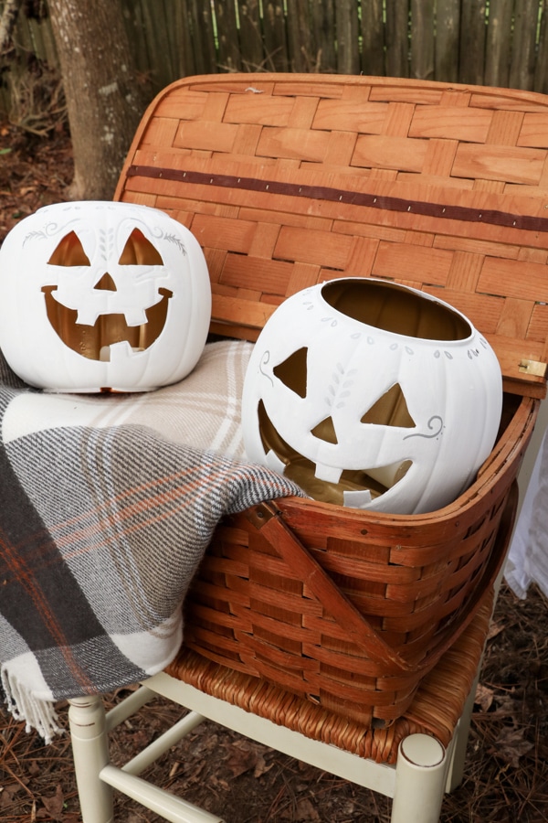 Basket full of white painted dollar store carved pumpkins and a fall blanket