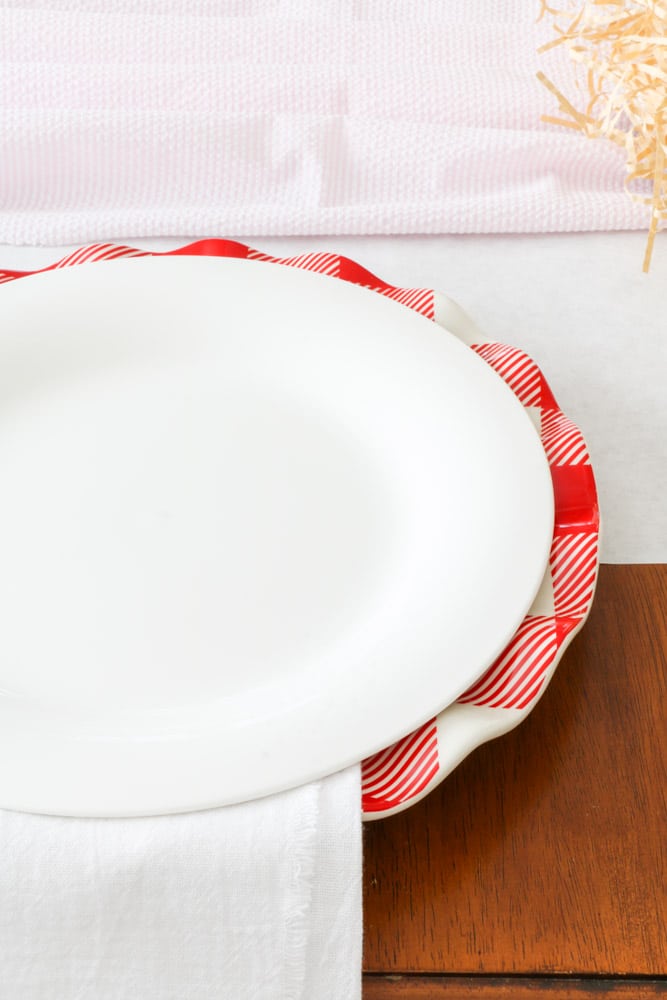 Valentine table setting with red and white buffalo check dinner plate and white plate stacked