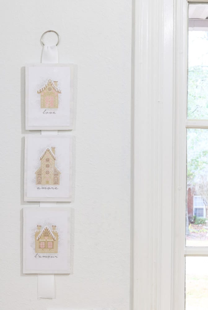 Three gingerbread printables attached to wood and hung by ribbon for decoration.