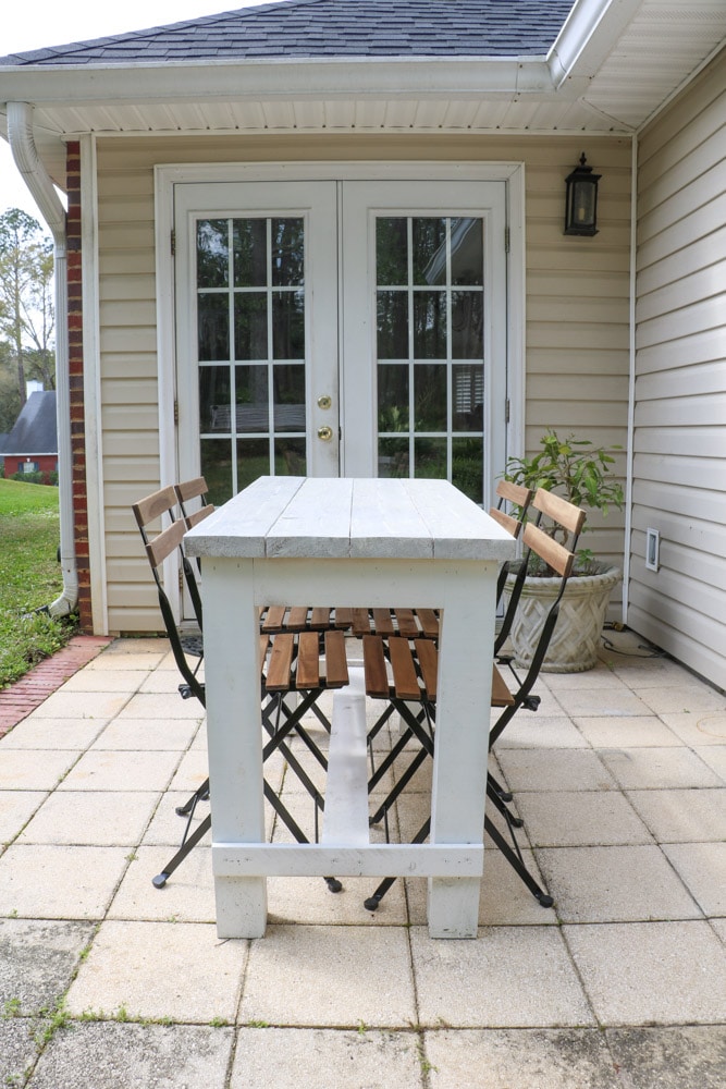 Farmhouse table and french folding bistro chairs on a back patio.