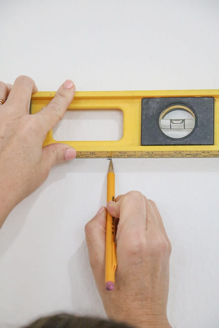 How to hang a gallery wall showing how to level for the nails.