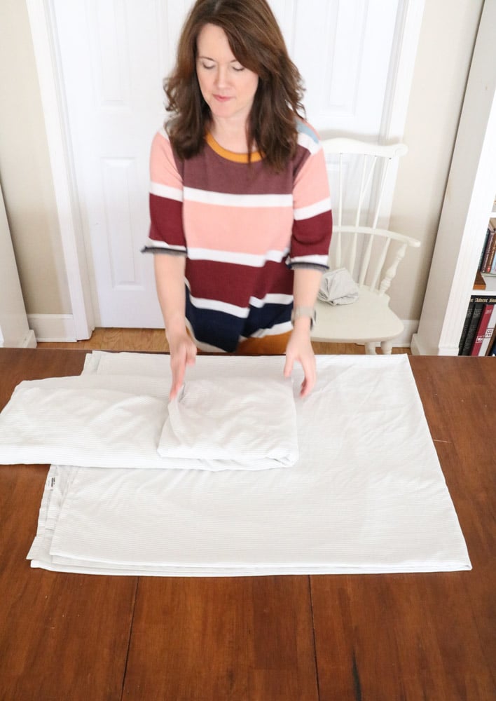 How to fold bed sheets neatly by taking the fitted sheet and folding it into a square.