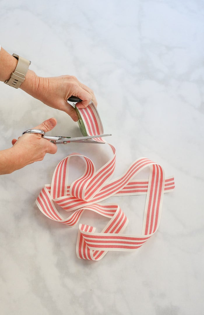 How to hang a wreath with ribbon on a window.  This simple DIY will show you two ways to hang wreaths on windows inside your home.  Start by measuring and cutting your ribbon.