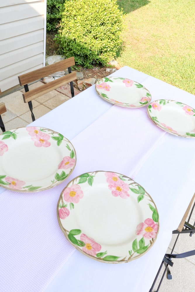 Garden party decoration ideas using white linen tablecloth, pink and white runner and desert rose dishes