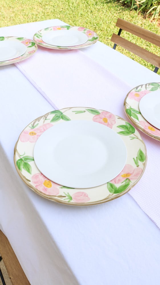 Garden party decoration ideas using white linen tablecloth, pink and white runner and desert rose dishes with a white salad plate in the middle