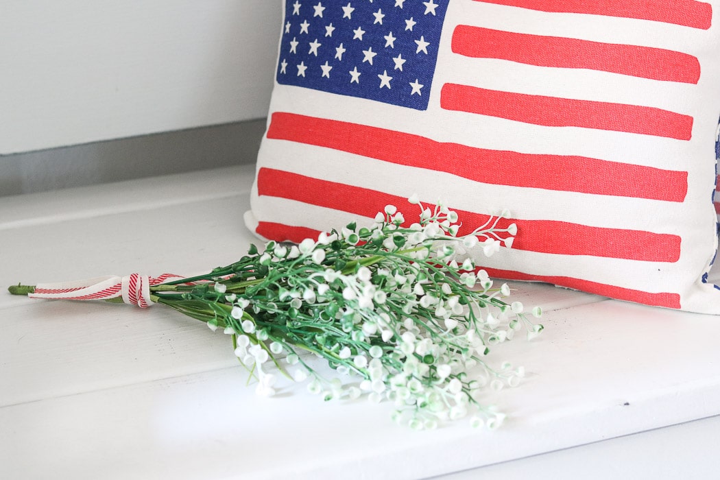 red, white and blue decorations in the entryway with American flag pillow and flowers